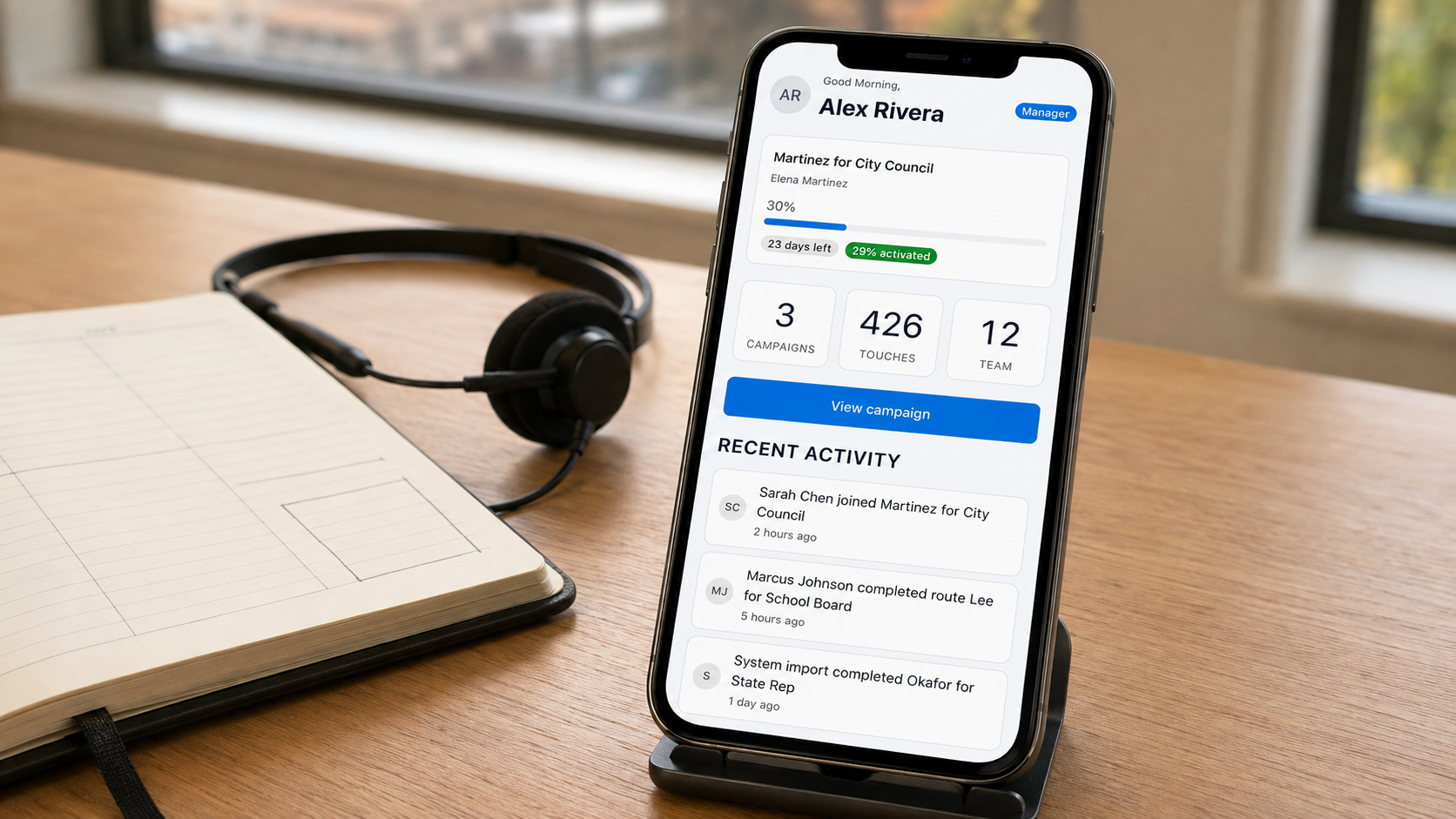 Illustration of the Activate dashboard on a phone beside a planner and headset; sample data